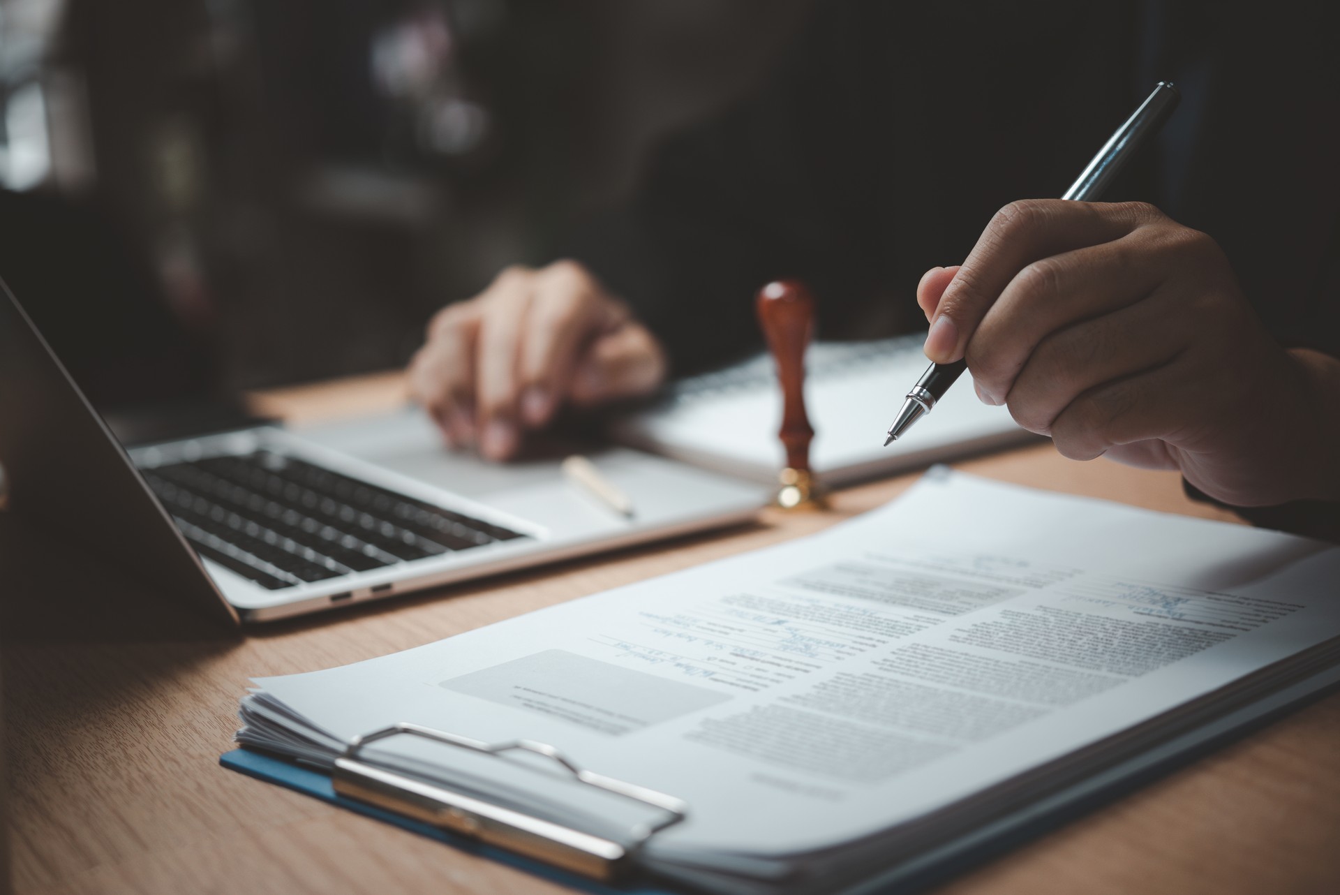 Man hand stamping approval signing on document or paperwork contract at desk.